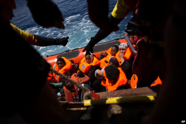 Women and children wait their turn to get on onboard the rescue vessel Golfo Azzurro by members of the Spanish NGO Proactiva Open Arms, after being rescued from a wooden boat sailing out of control in the Mediterranean Sea, about 18 miles north of Sabrath Libya, June 15, 2017.