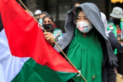 Seorang anggota organisasi buruh Indonesia memegang bendera Palestina saat melakukan aksi protes terhadap Israel di luar gedung PBB di Jakarta, 18 Mei 2021. (Foto: REUTERS/Ajeng Dinar Ulfiana)