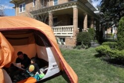 Warga AS, Andrew Kolb, sedang membaca buku dengan anaknya, James, 5, di dalam tenda yang didirikan di halaman rumah, selama masa isolasi di tengah penyebaran virus corona di Washington, U.S., April 2, 2020