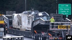 The engine from Monday's Amtrak train crash onto Interstate 5 is transported from the scene, Dec. 20, 2017, in DuPont, Wash. Three men were killed as a result of the derailment, which occurred after the train barreled into a 30-mph zone at 80 mph.