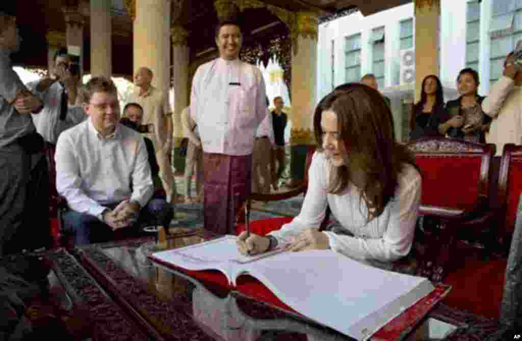 Denmark’s Crown Princess Mary signs the visitors' book next to Danish Minister for Development Cooperation Rasmus Helveg Petersen, left, during a visit to Shwedagon Pagoda, considered as Myanmar’s holiest Buddhist shrine, in Yangon Saturday, Jan. 11, 2014
