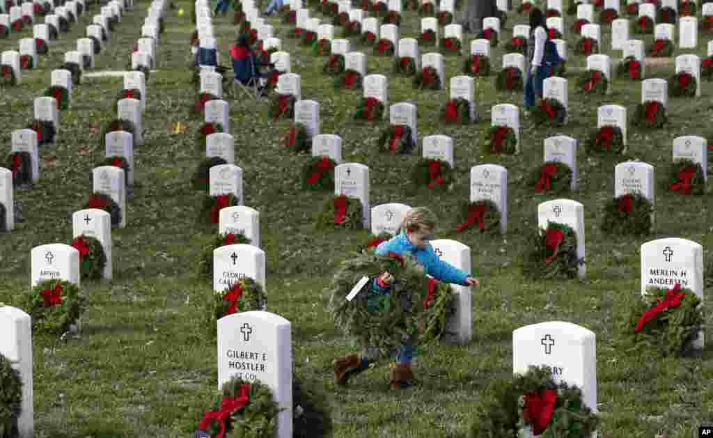 Lane Austin, 6, of Virginia Beach, carries a wreath to grave during Wreaths Across America at Arlington National Cemetery, in Arlington, Virginia, Dec. 12, 2015.