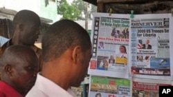 People read newspaper headlines commenting on U.S. President Barack Obama's announcement on sending troops to fight the Ebola virus in Monrovia, Liberia, Sept. 17, 2014.