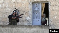 Un miembro del ejército libre de Siria habla con una mujer durante una patrulla en busca de fuerzas gubernamentales en Haram, Idlib, Siria.