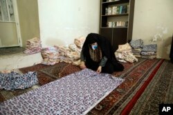 In a mosque in Tehran, Iran, a woman cuts bed sheets to make face masks for hospitals, April 5, 2020. (AP photo)