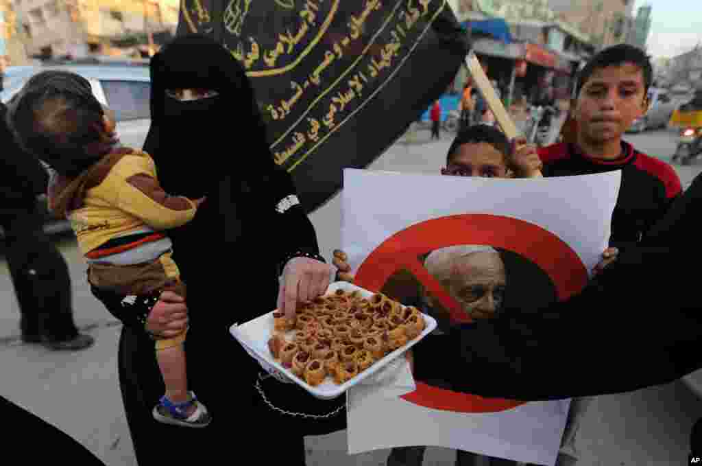 A Palestinian distributes sweets to pedestrians on a street in Khan Younis, southern Gaza Strip, after hearing of the death of former Israel Prime Minister Ariel Sharon, Jan. 11, 2014.