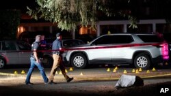 Police walk past evidence markers at a scene Thursday, Sept. 3, in Lacey, Wash., where a man suspected of fatally shooting a supporter of a right-wing group in Portland, Ore., last week was killed as investigators moved in to arrest him. (AP Photo/Ted Warren)