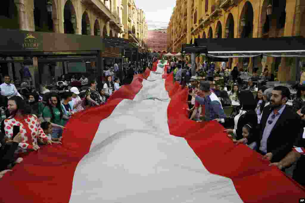 People carry a 300-meter-long Lebanese flag, part of a campaign to break a Guinness World Record, in downtown Beirut.