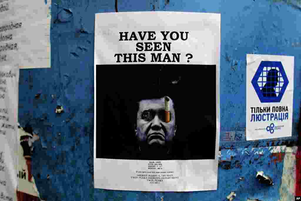 Um cartaz com a foto do Presidente ucraniano fugido, Viktor Yanukovich, está colado numa barricada no centro de Kiev, Fev. 27, 2014. 
