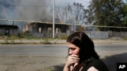 Một phụ nữ ngồi khóc trước căn nhà đang cháy sau các vụ pháo kích ở Donetsk, miền đông Ukraine, ngày 7/9/2014.