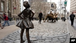 A statue titled "Fearless Girl" faces the Wall Street bull, Wednesday, March 8, 2017, in New York. 