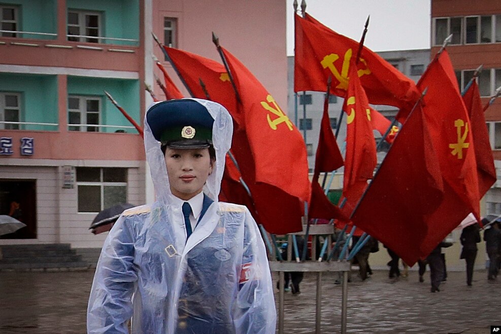 A North Korean traffic police woman directs vehicles at a street junction while behind her the sidewalk is decorated with flags of the ruling party, the Workers' Party in Pyongyang, North Korea.
