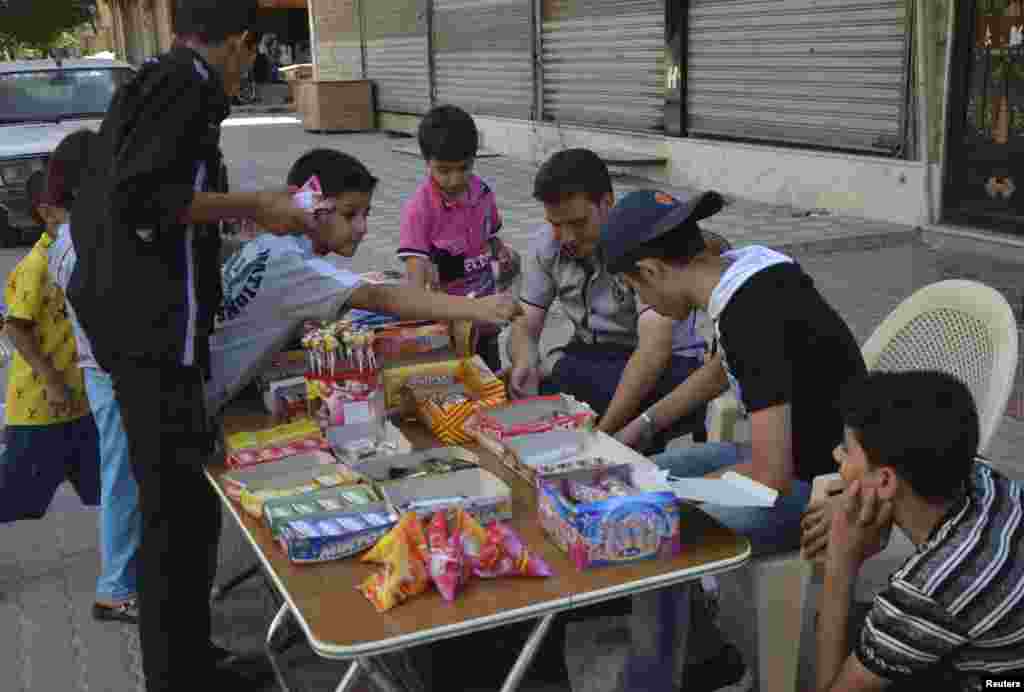Anak-anak membeli permen di kawasan Duma di Damaskus, Suriah, pada hari raya Idul Fitri, 8 Agustus 2013.