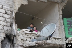 FILE - Children peer from a partially destroyed home in Aleppo, Syria, Feb. 11, 2016.