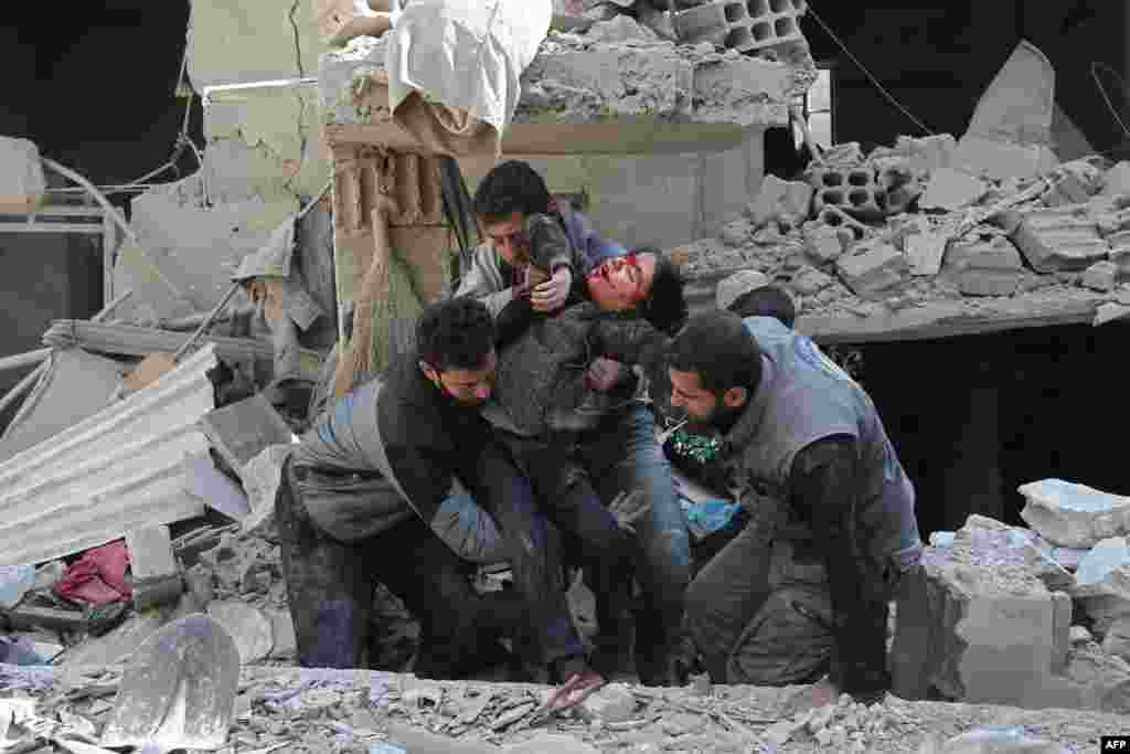 Syrians rescue a child following a reported government airstrike in the rebel-held town of Hamouria, in the besieged Eastern Ghouta region on the outskirts of the capital Damascus.