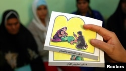 FILE - A counselor holds up cards used to educate women about female genital mutilation (FGM).
