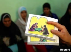 FILE - A counselor holds up cards used to educate women about female genital mutilation (FGM).