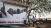 Sudanese boys walk past an election campaign banner in support of President Omar al-Bashir that reads "community commission in support of nominating Marshal Omar al-Bashir, in Khartoum, Sudan, April 11, 2015. 