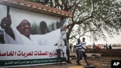 Sudanese boys walk past an election campaign banner in support of President Omar al-Bashir that reads "community commission in support of nominating Marshal Omar al-Bashir, in Khartoum, Sudan, April 11, 2015. 