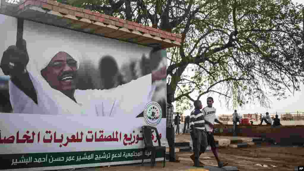 De jeunes soudanais passent devant une banderole de campagne électorale du président Omar el-Béchir, à Khartoum, au Soudan, le 11 avril 2015.