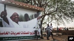 De jeunes soudanais se promènent devant une affiche de campagne électroale du président sortant Omar al-Bashir à Khartoum, Soudan, samedi 11 avril 2015. 