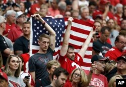 Arizona Cardinals and San Francisco 49ers fans hold the American flag during the national anthem prior to an NFL football game, Oct. 1, 2017, in Glendale, Arizona.