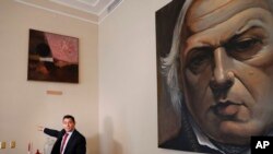 Carlos Vecchio, político exiliado que Estados Unidos reconoce como embajador de Venezuela, señala una sección vacía de una pared donde una vez colgaba una obra de arte en la residencia del embajador en Washington.
