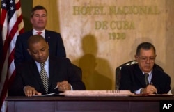 U.S.Transportation Secretary Anthony Foxx and Cuba's Minister of Transportation Adel Yzquierdo Rodriguez, right, sign the airline transportation agreement as Assistant Secretary of State for Economic and Business Affairs Charles Rivkin, top left, looks on in Havana, Cuba, Feb. 16, 2016.