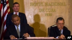 U.S.Transportation Secretary Anthony Foxx and Cuba's Minister of Transportation Adel Yzquierdo Rodriguez, right, sign the airline transportation agreement as Assistant Secretary of State for Economic and Business Affairs Charles Rivkin, top left, looks on