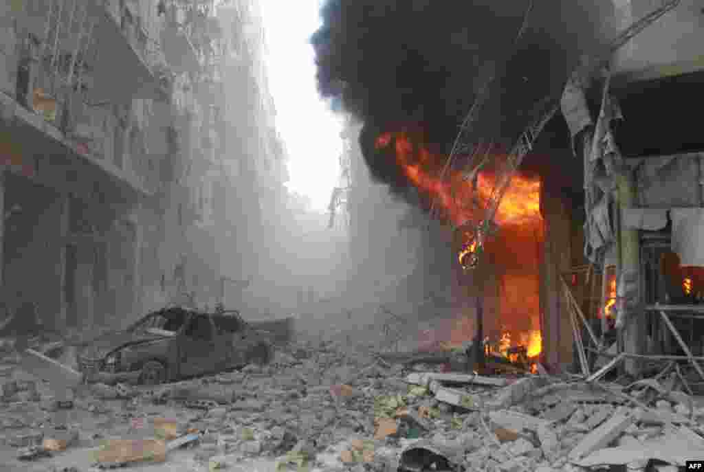 Debris cover a street and flames rise from a building following a reported air strike by Syrian government forces during the Friday prayer in the Sukkari neighborhood of the northern city of Aleppo. 