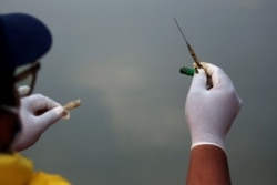 Ade Yunus, pendiri kelompok Bank Sampah Sungai Cisadane memegang jarum suntik bekas saat mengumpulkan sampah medis di sungai Cisadane, Tangerang (dok: REUTERS/Willy Kurniawan)