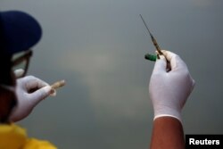 Ade Yunus, pendiri kelompok Bank Sampah Sungai Cisadane memegang jarum suntik bekas saat mengumpulkan sampah medis di sungai Cisadane, Tangerang (dok: REUTERS/Willy Kurniawan)
