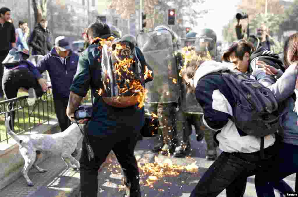 Protesters and police are hit by a gasoline bomb during a demonstration called for by students and teachers in downtown Santiago, Chile, June 17, 2015.