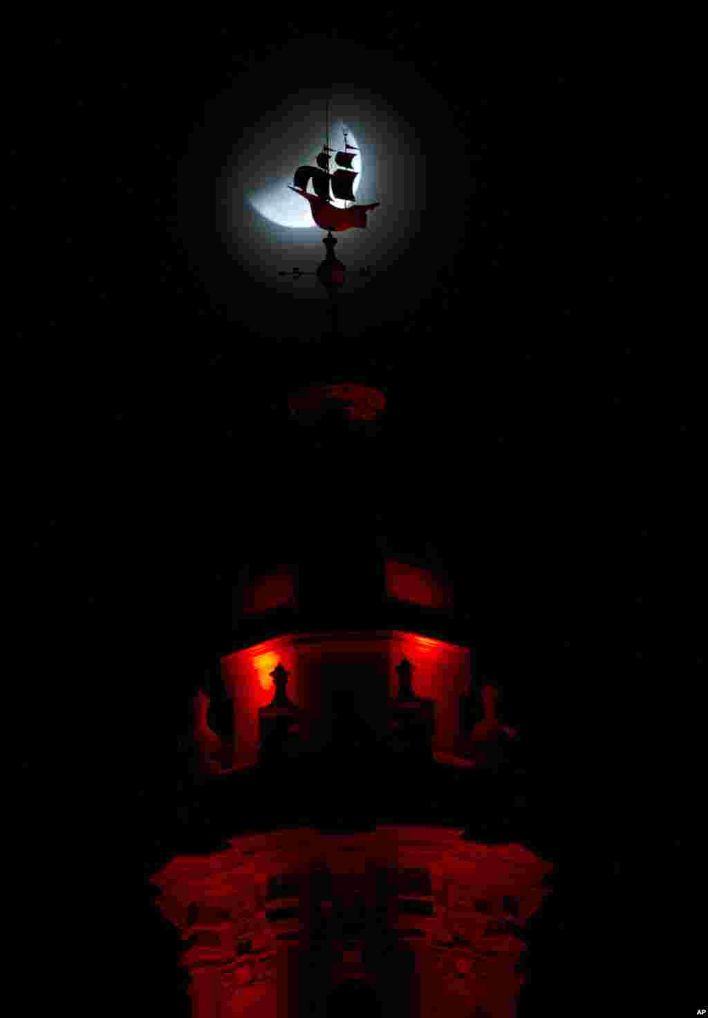 The Earth&#39;s shadow begins to cross over the moon during the total lunar eclipse, as it goes behind a weathervane shaped like a Spanish galleon on the Freedom Tower,&nbsp;in Miami, Florida, Oct. 8, 2014. 
