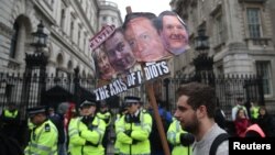 Demonstrators hold placards during a protest outside Downing Street in Whitehall, central London, Britain, April 9, 2016. 