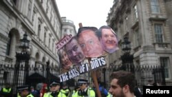 Demonstrators hold placards during a protest outside Downing Street in Whitehall, central London, Britain, April 9, 2016.