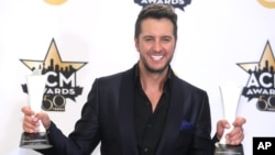 Luke Bryan poses in the press room with the awards for entertainer of the year and vocal event of the year at the 50th annual Academy of Country Music Awards, April 19, 2015, in Arlington, Texas. 