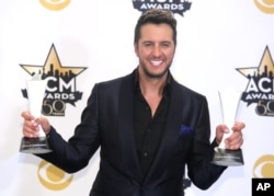 Luke Bryan poses in the press room with the awards for entertainer of the year and vocal event of the year at the 50th annual Academy of Country Music Awards at AT&T Stadium, April 19, 2015, in Arlington, Texas.