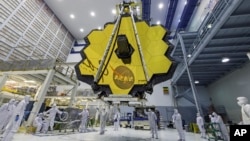 In this April 13, 2017 photo provided by NASA, technicians lift the mirror of the James Webb Space Telescope using a crane at the Goddard Space Flight Center in Greenbelt, Md. (Laura Betz/NASA via AP)