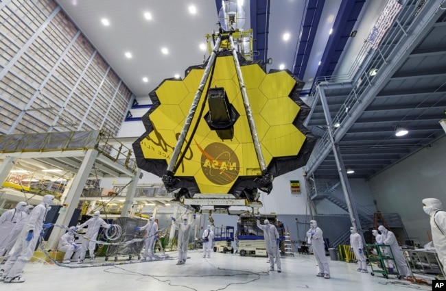 In this April 13, 2017 photo provided by NASA, technicians lift the mirror of the James Webb Space Telescope using a crane at the Goddard Space Flight Center in Greenbelt, Md. (Laura Betz/NASA via AP)