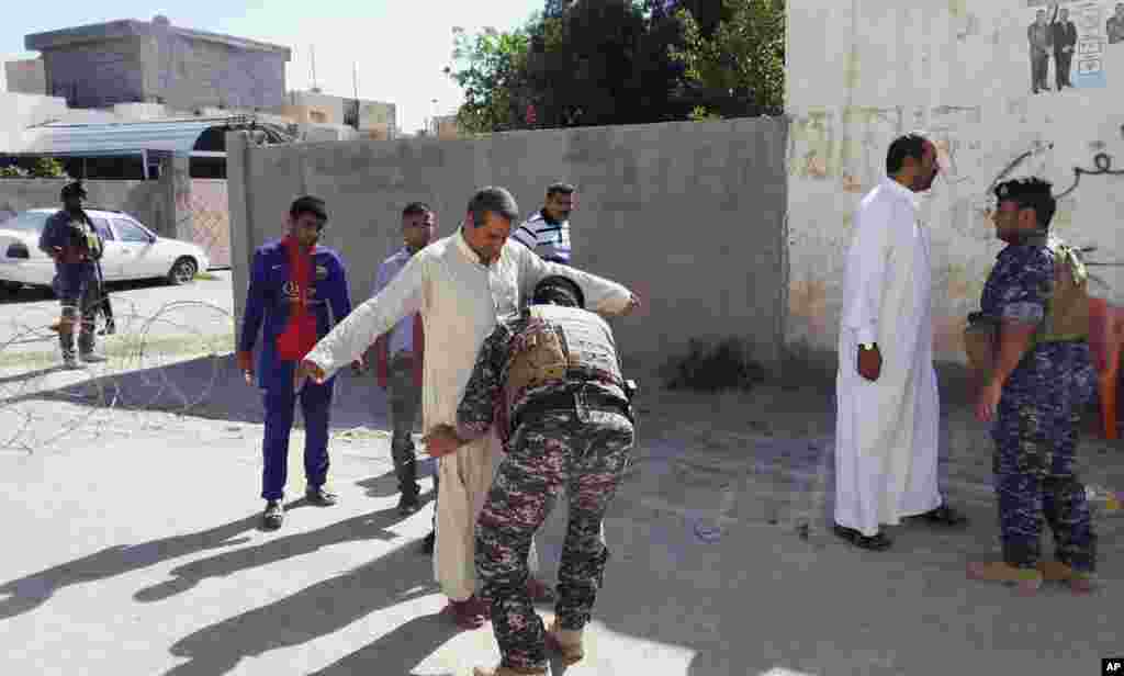 Security forces search people outside a polling station in Habaniyah, near Fallujah, April 30, 2014.