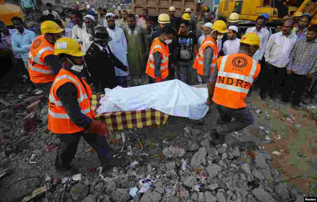 Rescue workers use a stretcher to carry the body of a victim across the rubble after the collapse of a residential building in Thane district, on the outskirts of Mumbai, April 6, 2013.