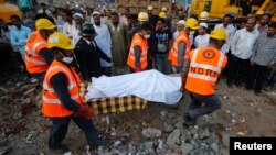 Rescue workers use a stretcher to carry the body of a victim across the rubble after the collapse of a residential building in Thane district, on the outskirts of Mumbai, Apr. 6, 2013. 