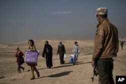 FILE - Displaced people leave their homes during fighting in Hamam al-Alil, south of Mosul, Iraq, Nov. 6, 2016.