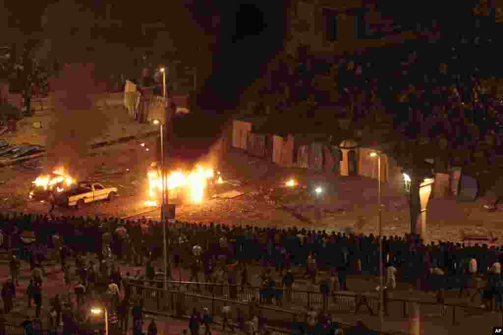 Pro-government demonstrators, bottom, watch as cars burn during clashes with anti-government demonstrators, top, in Tahrir square, Feb. 3, 2011.