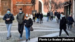 Orang-orang mengenakan masker berjalan-jalan di alun-alun Kota Codogno, Italia, satu tahun setelah kota itu menjadi pusat wabah pandemi COVID-19 di Eropa, 11 Februari 2021. (Foto: Flavio Lo Scalzo/Reuters)