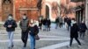 Orang-orang mengenakan masker berjalan-jalan di alun-alun Kota Codogno, Italia, satu tahun setelah kota itu menjadi pusat wabah pandemi COVID-19 di Eropa, 11 Februari 2021. (Foto: Flavio Lo Scalzo/Reuters)