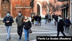 Orang-orang mengenakan masker berjalan-jalan di alun-alun Kota Codogno, Italia, satu tahun setelah kota itu menjadi pusat wabah pandemi COVID-19 di Eropa, 11 Februari 2021. (Foto: Flavio Lo Scalzo/Reuters)