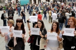 Wartawan Bosnia mengangkat spanduk bertuliskan "Jurnalisme bukan kejahatan" dan "Hentikan kekerasan terhadap wartawan," di pusat kota Sarajevo untuk memprotes pemukulan terhadap seorang jurnalis di Banja Luka, kota utama di bagian Bosnia yang dikelola Serbia, 28 Agustus 2018. (Foto: AP)