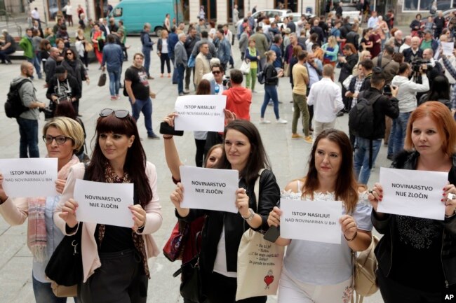 Wartawan Bosnia mengangkat spanduk bertuliskan "Jurnalisme bukan kejahatan" dan "Hentikan kekerasan terhadap wartawan," di pusat kota Sarajevo untuk memprotes pemukulan terhadap seorang jurnalis di Banja Luka, kota utama di bagian Bosnia yang dikelola Serbia, 28 Agustus 2018. (Foto: AP)